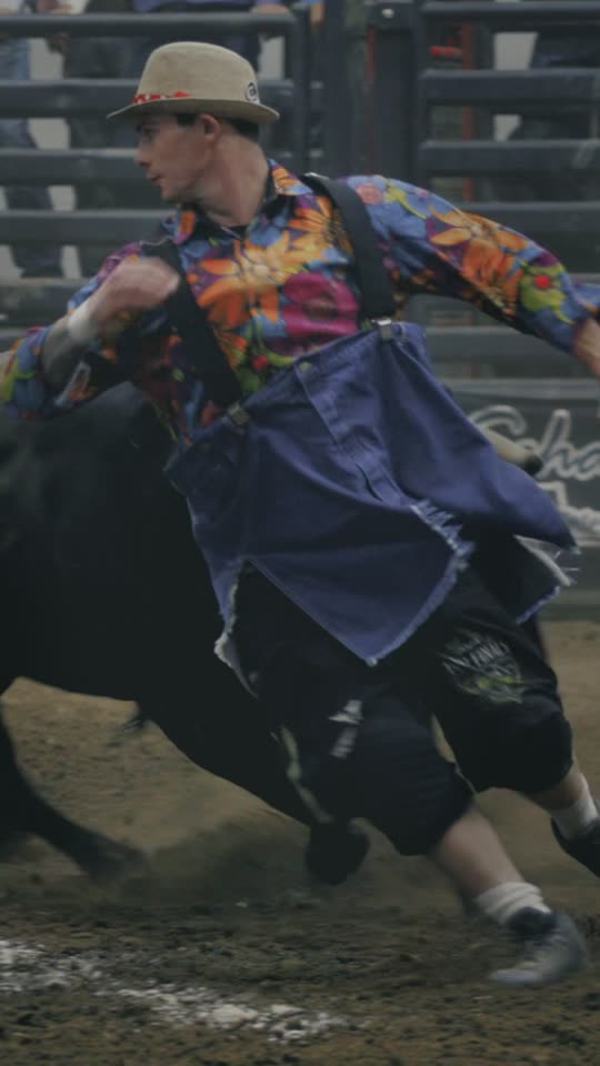 A bullfighter in a patterned shirt colliding with a black bull